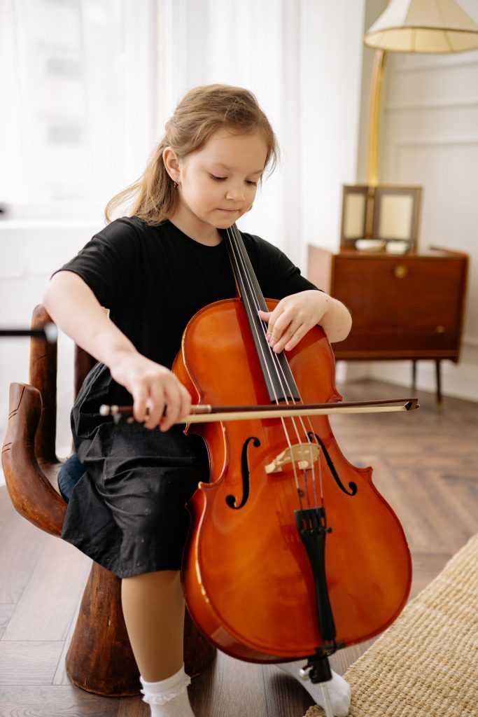Une petite fille joue du violoncelle chez elle